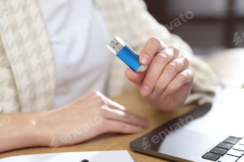 Preview: Woman with USB flash drive at wooden desk, closeup