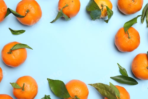 Preview: Fresh ripe tangerines and green leaves on light blue background, flat lay. Space for text
