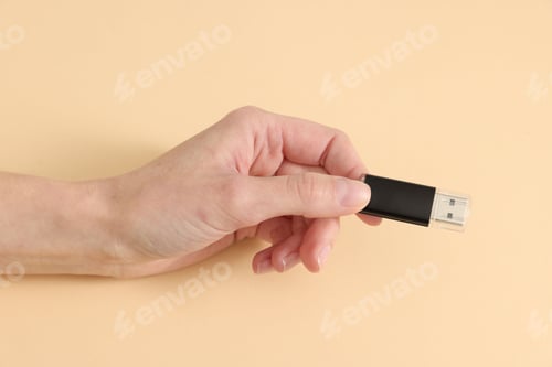 Preview: Woman with USB flash drive on beige background, closeup