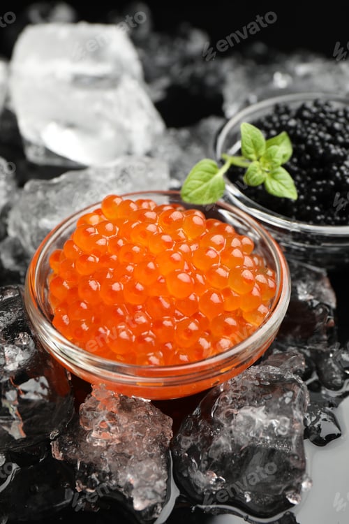 Preview: Delicious red and black caviar with basil, ice cubes on black mirror table, closeup