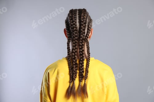 Preview: Teenage girl with beautiful braids on grey background, back view