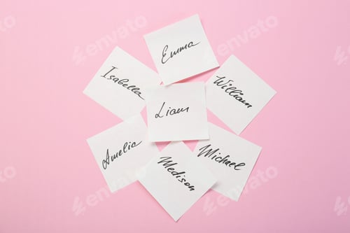 Preview: Paper stickers with different names on pink background, top view. Choosing baby's name