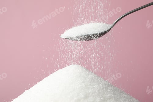 Preview: Pouring granulated sugar onto pile against pink background, closeup