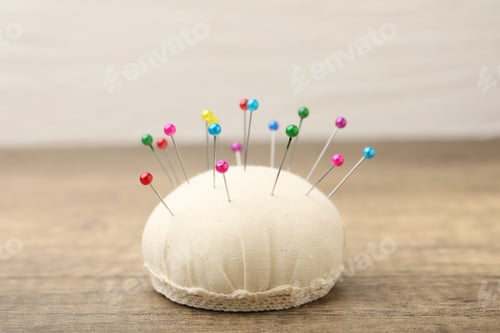 Preview: Pincushion with pins on wooden table, closeup