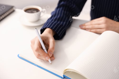 Preview: Woman writing in notebook with pen at table, closeup