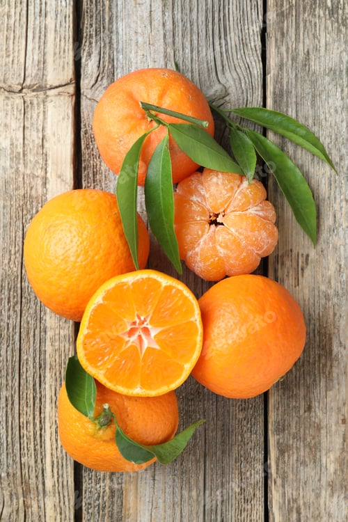 Preview: Fresh tangerines and green leaves on wooden table, flat lay