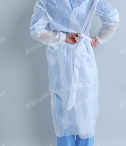 Preview: Medical worker tying disposable isolation gown on light background, closeup