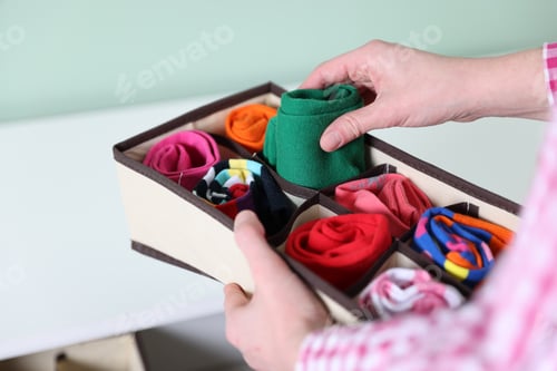Preview: Woman putting with socks into organizer on shelf indoors, closeup