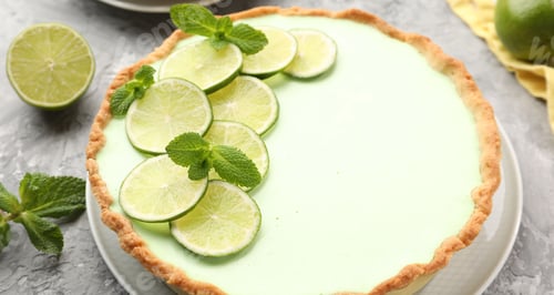 Preview: Tasty lime pie with fruit slices and mint leaves on grey textured table, closeup