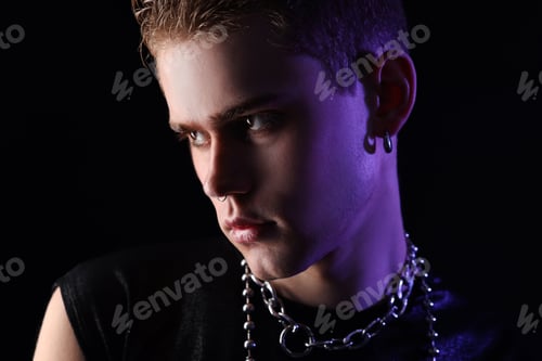 Preview: Young man in stylish clothes and accessories in color light on black background, closeup