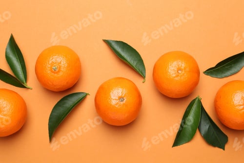 Preview: Fresh ripe tangerines and leaves on orange background, flat lay