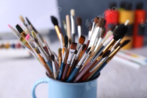 Preview: Paintbrushes in holder and paints on table, closeup