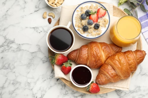 Preview: Healthy breakfast. Tasty croissants, jam, oatmeal with berries, orange juice and coffee on white mar