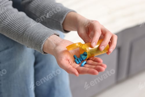 Preview: Woman pouring pills from bottle on sofa indoors, closeup
