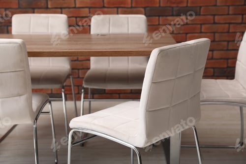Preview: Stylish comfortable chairs and wooden table in office, closeup