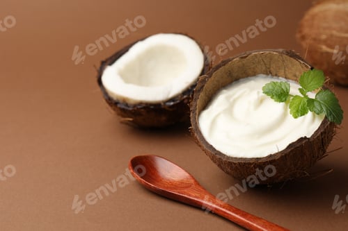 Preview: Tasty coconut yogurt with melissa leaves in shell and nuts on brown background, closeup. Space for t