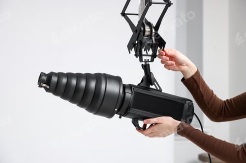 Preview: Woman with professional lighting equipment in photo studio, closeup