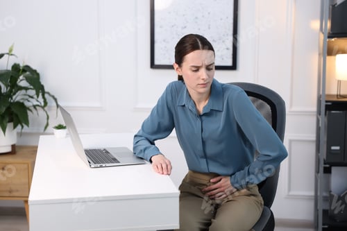 Preview: Young woman suffering from menstrual pain at workplace