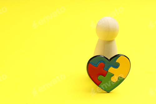 Preview: Autism. Human figure and heart made of puzzle pieces on yellow background, closeup. Space for text