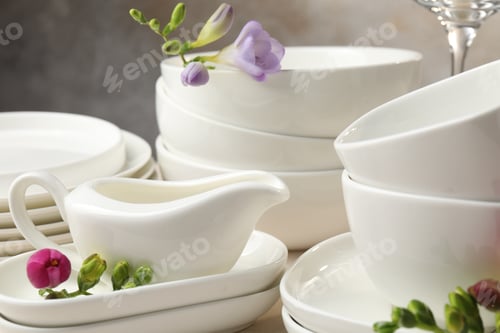 Preview: Clean dishware and beautiful flowers on light table, closeup
