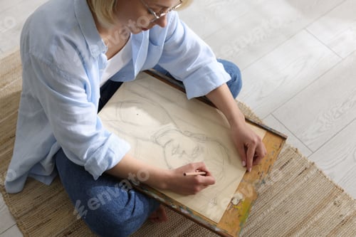 Preview: Woman drawing picture with pencil on floor indoors, above view
