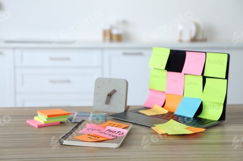 Preview: Laptop with colorful sticky notes, stationery and alarm clock on wooden table indoors, selective foc