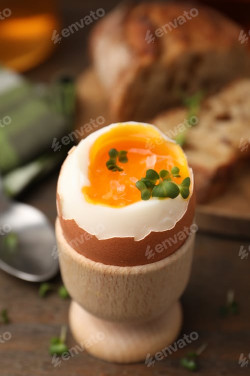 Preview: Tasty breakfast with soft boiled egg, microgreens and bread on wooden table, closeup