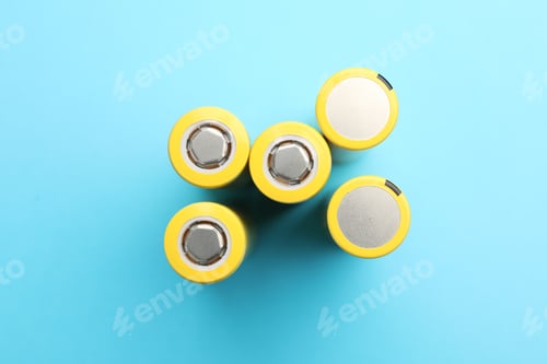 Preview: Many alkaline batteries on light blue background, flat lay