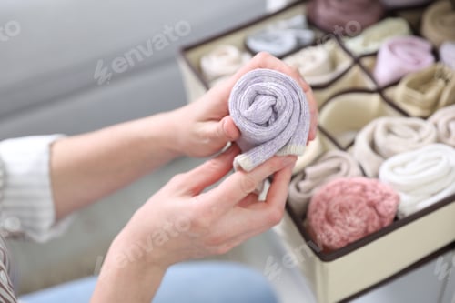 Preview: Woman putting with socks into organizer on shelf indoors, closeup
