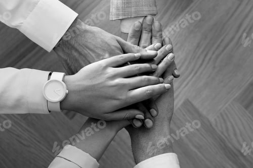 Preview: Group of people stacking their hands together, top view. Black-and-white toning