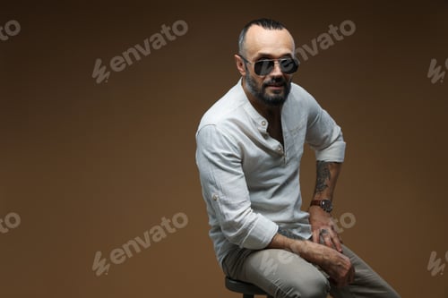Preview: Fashion model. Handsome man in sunglasses on brown background, space for text