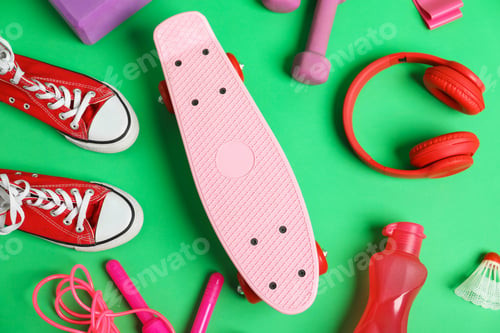 Preview: Penny board, water bottle, sneakers and sports equipment on green background, flat lay