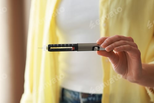 Preview: Diabetes. Woman with autoinjector at home, closeup