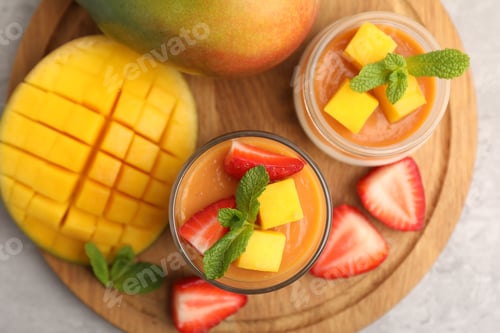 Preview: Delicious mango panna cotta, fruits and mint on grey table, top view