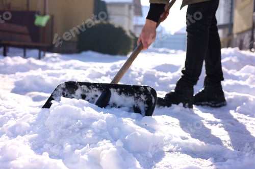 Preview: Man removing snow with shovel outdoors on winter day, closeup
