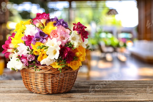 Preview: Beautiful freesia flowers in wicker basket on wooden table indoors