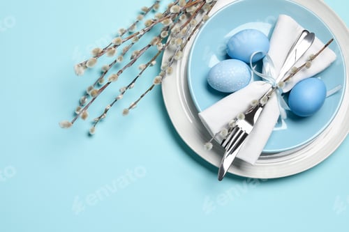 Preview: Easter celebration. Festive table setting with willow branches and painted eggs on light blue backgr