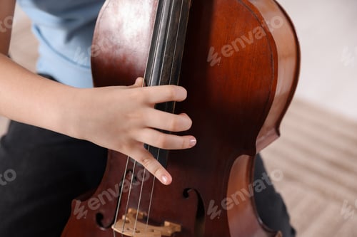 Preview: Little boy playing violoncello at home, closeup
