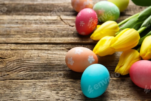 Preview: Painted Easter eggs and beautiful tulips on wooden table, closeup. Space for text