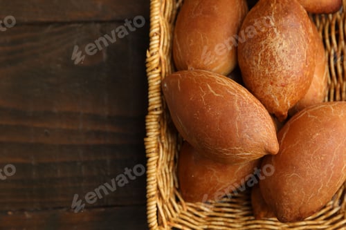 Preview: Delicious baked patties in basket on wooden table, top view