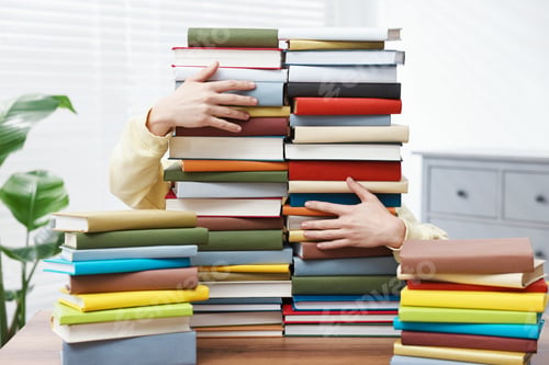 Preview: Man with many books at table indoors