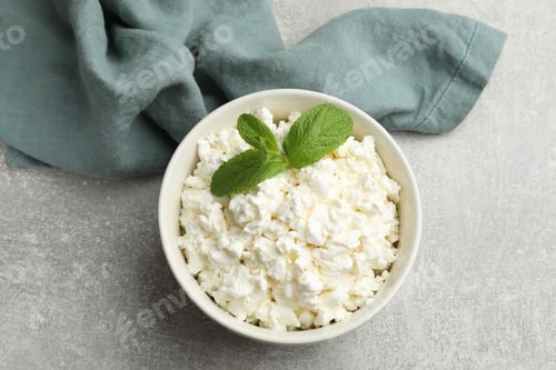 Preview: Fresh cottage cheese with mint in bowl on grey table, top view