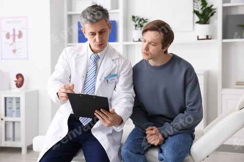 Preview: Urologist showing clipboard to patient on medical couch in clinic