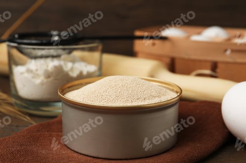 Preview: Dry yeast in bowl, flour, egg and rolling pin on table, closeup