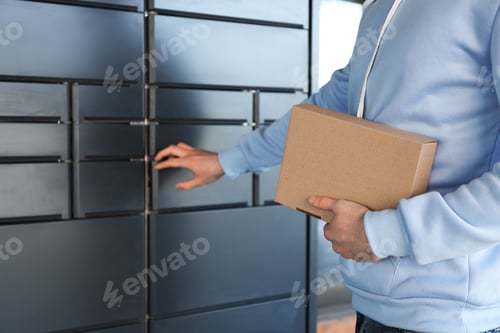 Preview: Man taking out cardboard box from parcel locker outdoors, closeup
