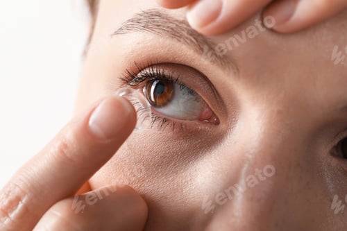 Preview: Woman putting on contact lenses against light background, closeup