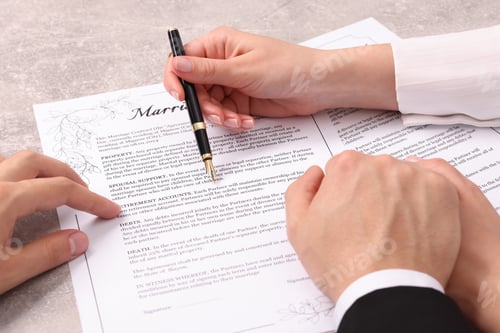 Preview: Man and woman signing marriage contract at light grey table, closeup