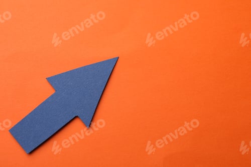 Preview: Blue paper arrow on orange background, top view. Space for text