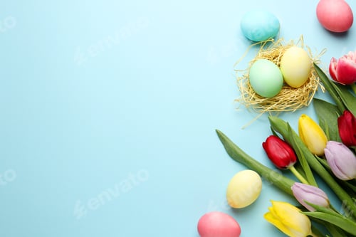 Preview: Painted Easter eggs and beautiful tulips on light blue background, flat lay. Space for text