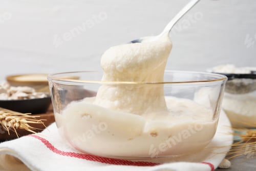 Preview: Taking dough with spoon from bowl at grey table, closeup